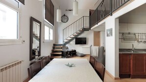Un comedor amplio con una mesa larga, una escalera y una zona de cocina.