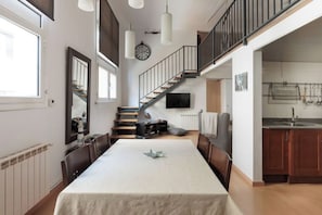 A spacious dining area with a long table, a staircase, and a kitchen area.