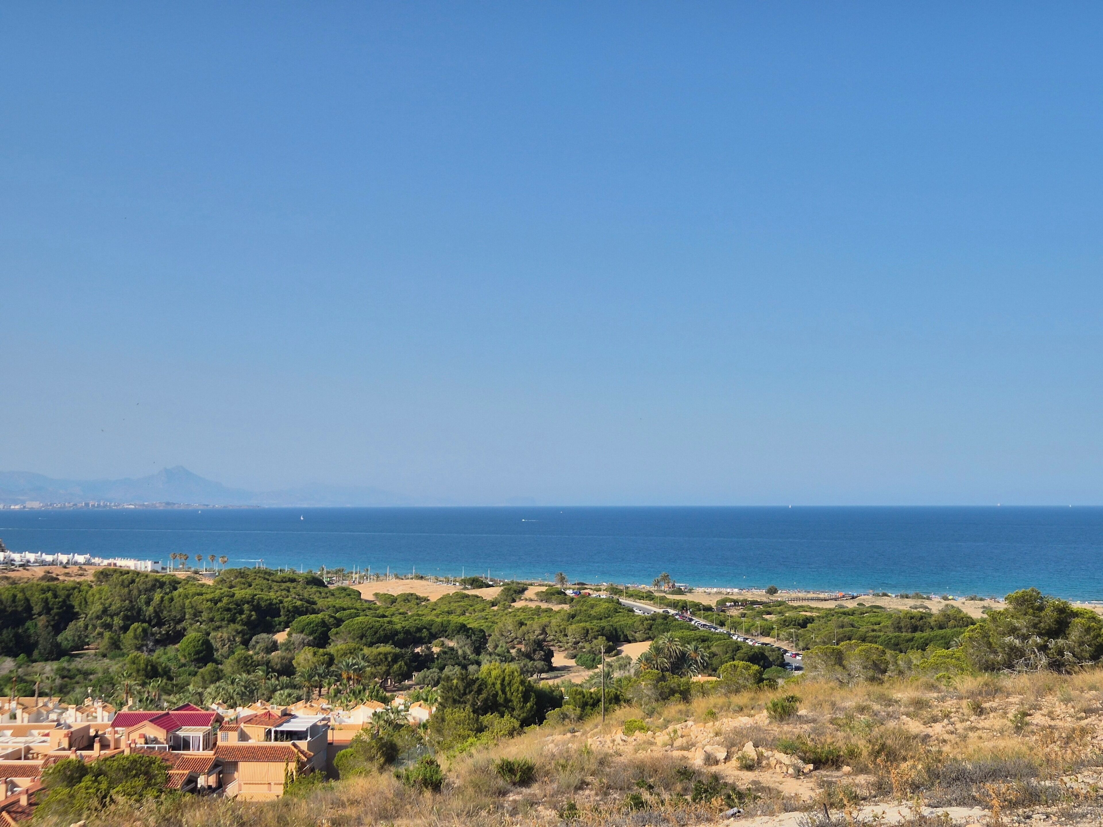 Zona costera con edificios, una carretera y una playa.