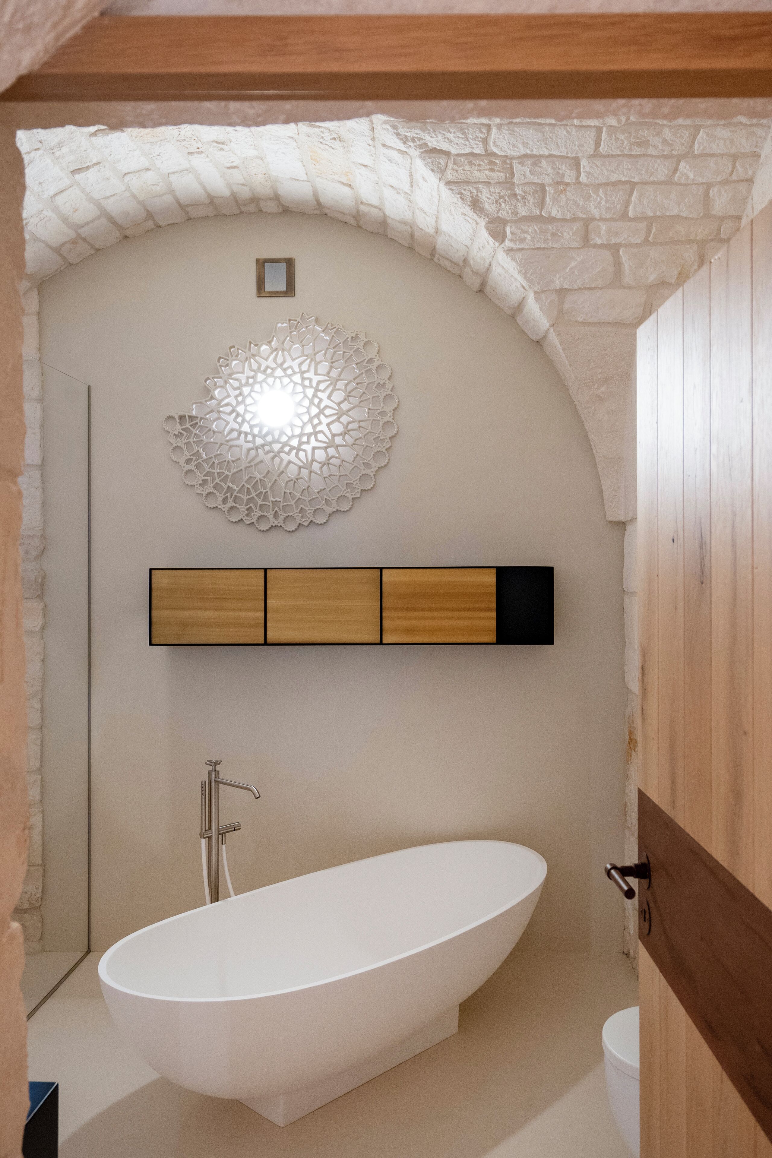 Une salle de bain moderne avec une baignoire sur pieds, un élément décoratif mural et une étagère en bois.