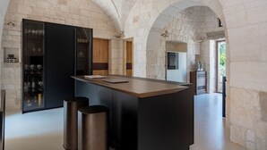 Una cocina moderna con arcos de piedra, una isla central y electrodomésticos integrados.