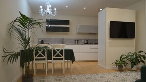 A modern kitchen with white cabinets, a black countertop, and a built-in oven. There is a dining area with a white table and chairs, and a chandelier above. - The Prince's Palace, a historic mansion (Abruzzo)