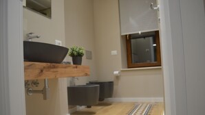 A modern bathroom with a wooden vanity, a black sink, a potted plant, and a patterned floor. - The Prince's Palace, a historic mansion (Abruzzo)