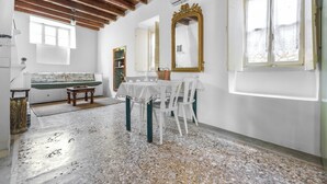 A room with a wooden ceiling, white walls, a white table with chairs, a bench, and a large mirror. - Old Town Charm – Casa Historica (Ermioni)