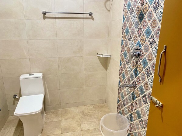 A small bathroom with a toilet, a shower, and a sink. - Serene Guest House (Vanur)