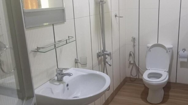 Un baño pequeño y limpio con lavamanos, inodoro y ducha.