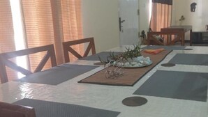 A dining area with a table set for four, featuring a placemat, a bowl of fruit, and a decorative plant. - The Garden Resort Airport Katunayaka (Katunayake)
