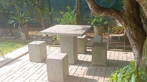 A concrete outdoor seating area with a table and chairs, surrounded by potted plants and trees. - The Garden Resort Airport Katunayaka (Katunayake)