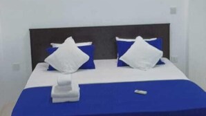 A bedroom with a bed, pillows, a blanket, and a red rug. - The Garden Resort Airport Katunayaka (Katunayake)