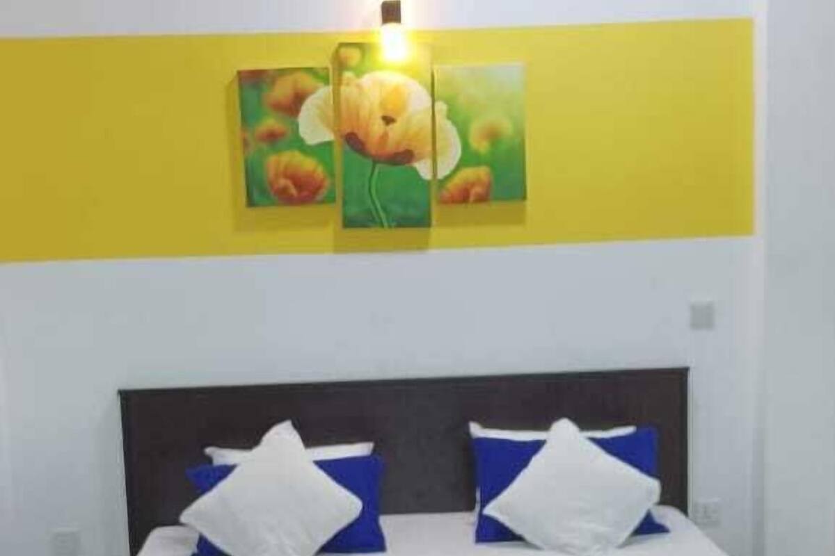 Ein Schlafzimmer mit einem Bett, Kissen, einer Decke und einem roten Teppich.