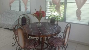 A dining area with a round table, four chairs, and a vase with flowers.