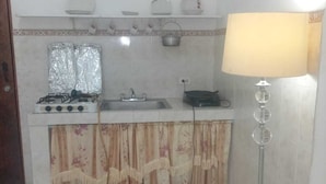 A small kitchen with a gas stove, sink, and a floor lamp.