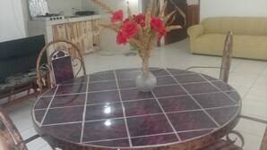 A dining area with a round table, chairs, and a vase with red flowers.