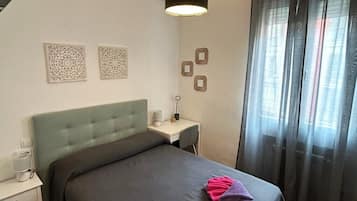 A bedroom with a bed, bedside table, lamp, and curtains.