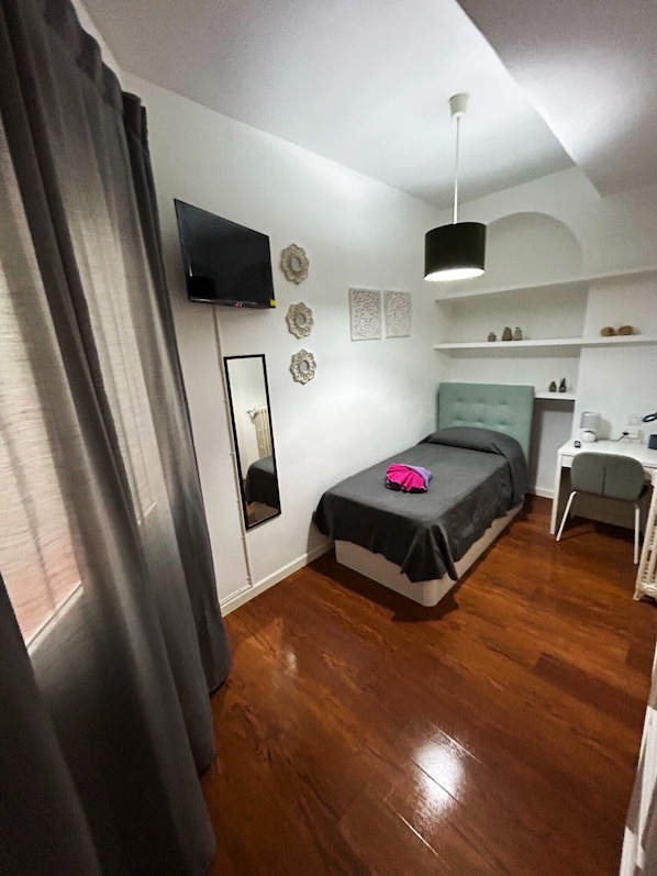 A modern bedroom with a bed, a desk, and a TV. - Habitaciones Magdalena (Madrid)