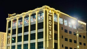 A multi-story hotel with a prominent 'HOTEL' sign on the facade, large windows, and a well-lit entrance. - Princess Plaza hotel (Ma'an)