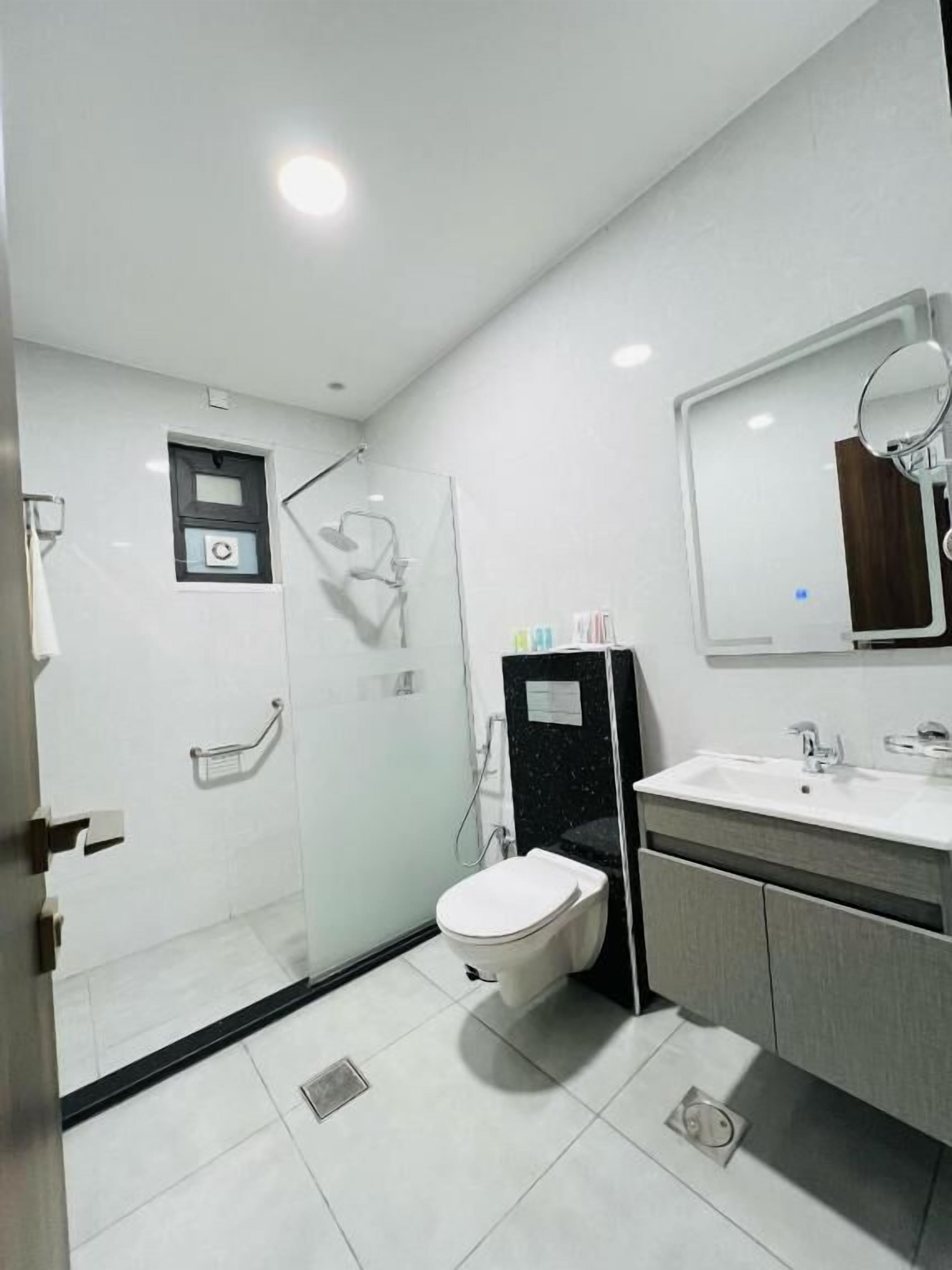 Ein modernes Badezimmer mit Duschkabine aus Glas, Toilette, Waschbecken mit Spiegel und Schrank.