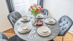 Una mesa redonda para seis personas con sillas tapizadas en gris, un florero y un cuenco decorativo.
