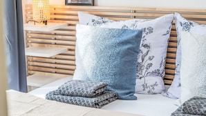 Un dormitorio ordenado con cabecera de madera, lámpara de noche e impresión enmarcadas de motivos botánicos en la pared.