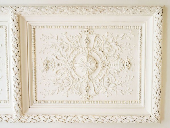 Un panel blanco decorativo con un diseño floral ornamentado, enmarcado por un borde texturizado.