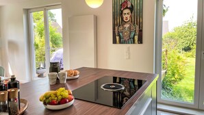 Une cuisine moderne dotée d’une plaque de cuisson à induction intégrée, d’un panier à fruits et d’un tableau accroché au mur.