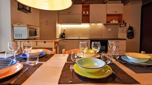 Un comedor con una mesa dispuesta para seis comensales, microondas y una cocina al fondo.