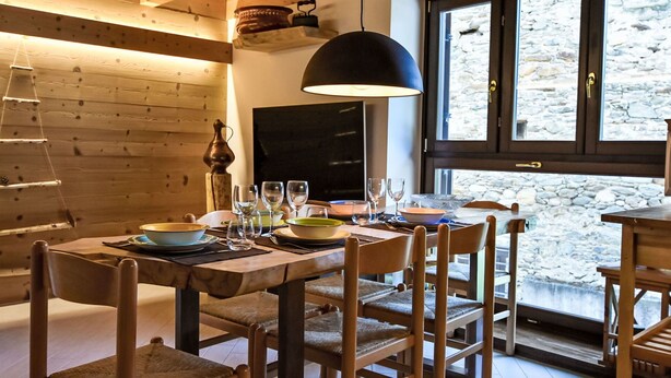 Un comedor rústico de madera con pared de piedra y un ventanal grande.