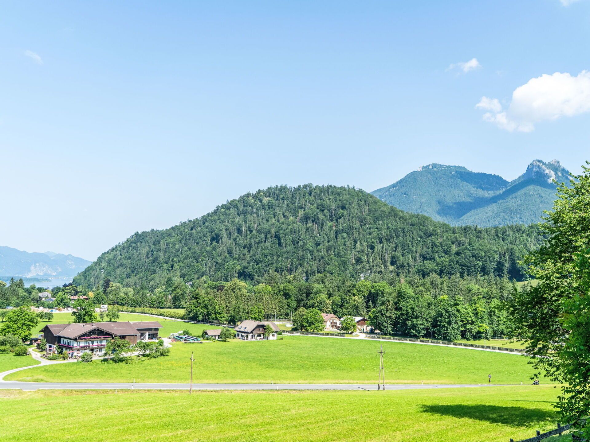 A rural landscape with a mountain, houses, and a clear sky.