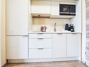 A compact kitchen with white cabinetry, a microwave, and a sink. - Nice apartment for 3 guests with WIFI, A/C, TV and balcony (Strobl)