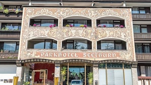 Een meerlaags gebouw met verfijnde architectonische details en balkons. De tekst op het bord zegt 'Parkhotel Seeturni'.
