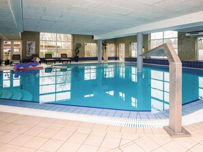 An indoor swimming pool with clear blue water, tiled walls, and a few lounge chairs. - 4 Person Holiday Park Home in Romo (Rømø)