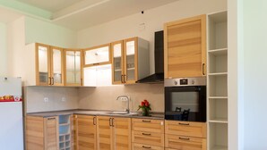 A modern kitchen with wooden cabinets, a built-in oven, and a refrigerator.