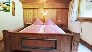 A wooden bed with checkered bedding, a wooden headboard, and a small bedside table. - Lovely apartment for 4 people (Hippach)