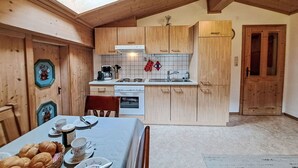 A kitchen with wooden cabinets, a stove, and a dining table set with bread and cups. - Lovely apartment for 4 people (Hippach)