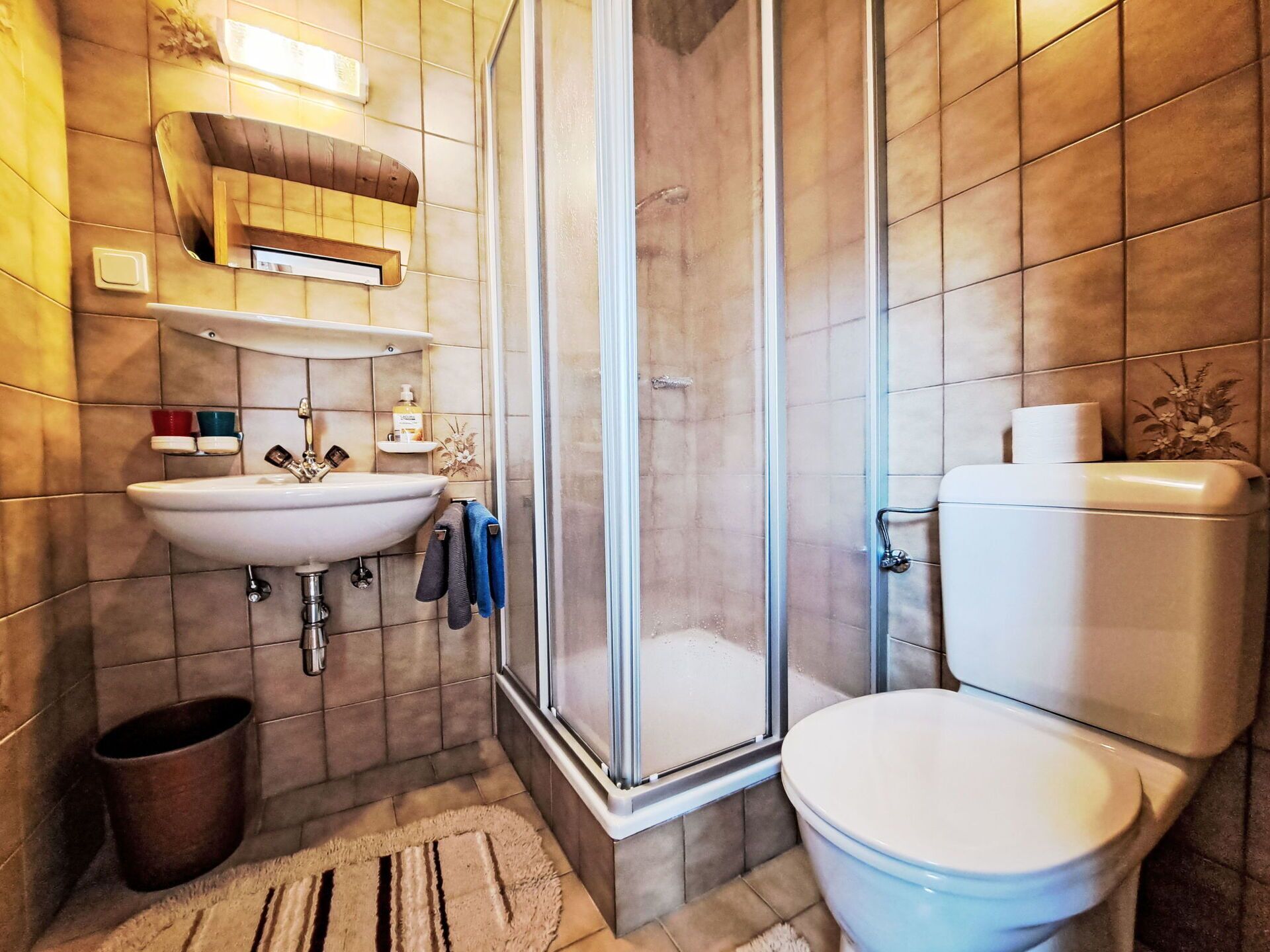 Ein modernes Badezimmer mit Dusche, Toilette, Waschbecken und einem Spiegel über dem Waschbecken.