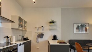 A modern kitchen with a central island, built-in appliances, and a dining area with a table and chairs. - Nice apartment for 2 guests with TV and balcony (Magdeburg)