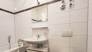 A modern bathroom with a bathtub, a sink, a toilet, and a mirror. - Nice apartment for 2 guests with TV and balcony (Magdeburg)