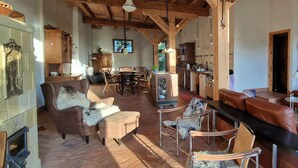 Amplia sala de estar con chimenea, vigas de madera en el techo y zona de comedor con una mesa grande y sillas.