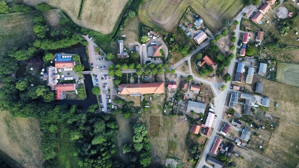 An aerial view of a small village with a mix of residential buildings, a church, and a river.