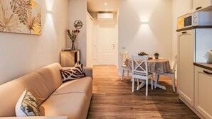 Un área de estar acogedora con un sofá, una mesa de comedor con sillas y una cocina con refrigerador.