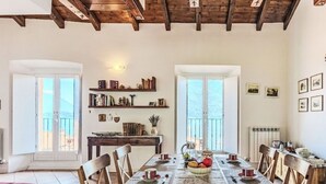 Un comedor con una mesa de madera, sillas, un frutero y estanterías.