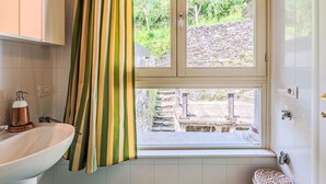 Un baño con ventana, lavamanos y zona de ducha.