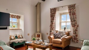 A cozy living room with a fireplace, a sofa, a chair, and a table with a tray of items.