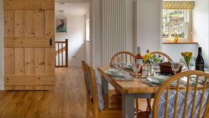 A dining area with a wooden table set for two, a sliding barn door, and a window with a view of the outdoors.