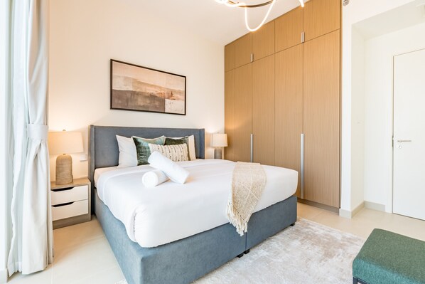 A modern bedroom with a large bed, a wardrobe, and a painting on the wall.