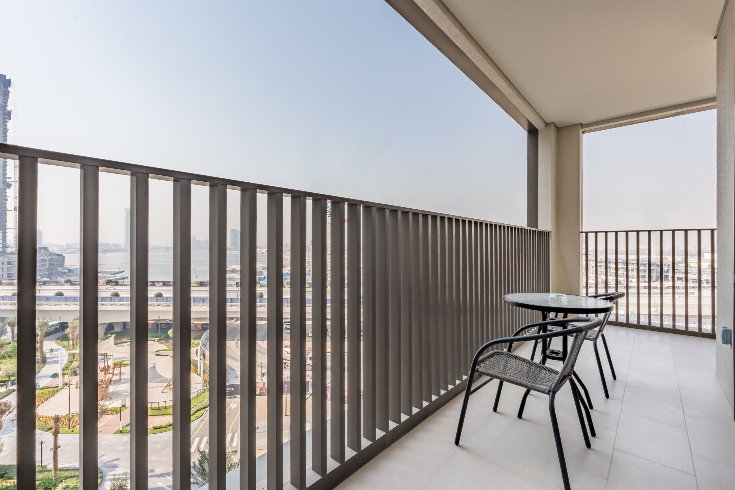 Een balkon met uitzicht op een stadsgezicht, een tafel met stoelen en een hekwerk.