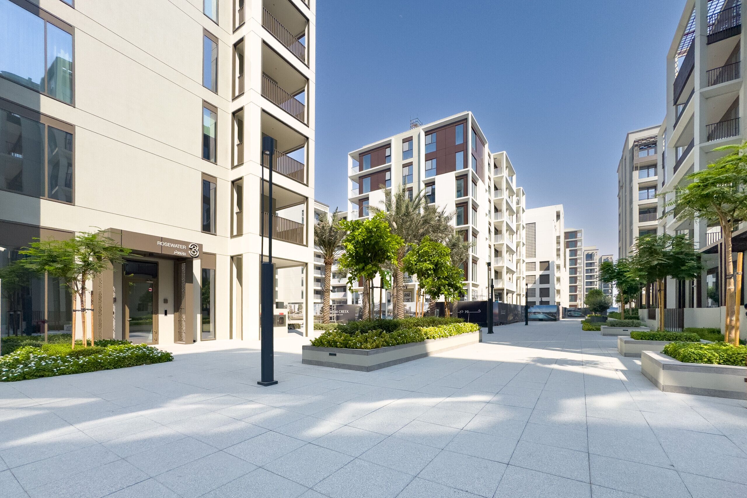 A modern urban plaza with contemporary buildings, a central open space, and landscaped areas.