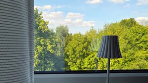 Una ventana con vistas a árboles verdes y un cielo despejado.