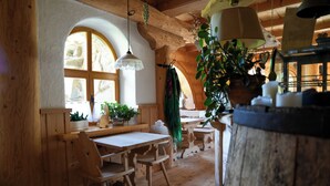 A rustic wooden interior with a wooden table and chairs, a hanging light fixture, and a barrel.