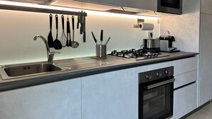 A modern kitchen with a stainless steel sink, gas stove, oven, and a microwave.